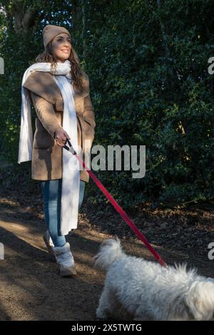 Frau mit Hund, die am Winternachmittag spazieren geht Stockfoto