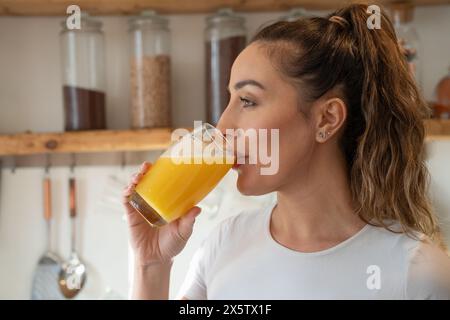 Frau in der Küche, die Orangensaft trinkt Stockfoto