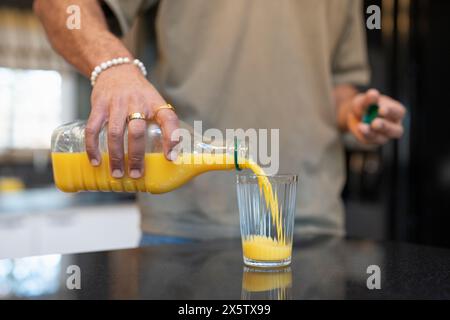 Nahaufnahme eines Mannes, der Orangensaft in Glas gießt Stockfoto