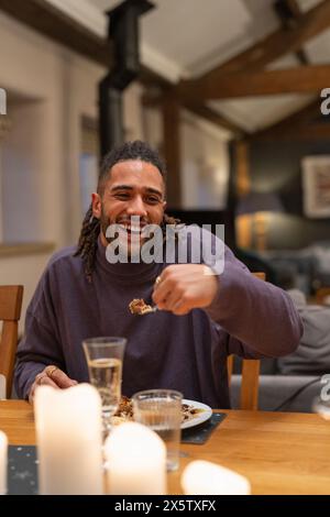 Ein lächelnder Mann isst am Tisch zu Abend Stockfoto