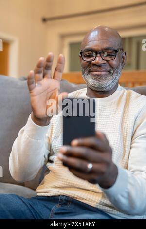 Lächelnder Senior-Mann, der Videoanruf am Telefon hat Stockfoto