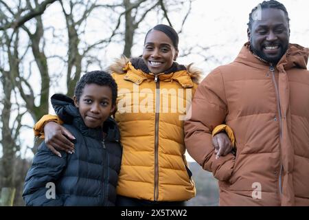 Junge mit Eltern in Winterjacken, die in ländlicher Umgebung spazieren gehen Stockfoto