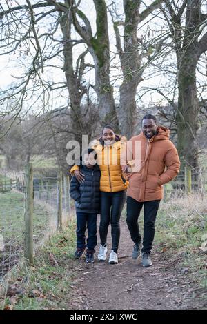 Junge mit Eltern in Winterjacken, die in ländlicher Umgebung spazieren gehen Stockfoto