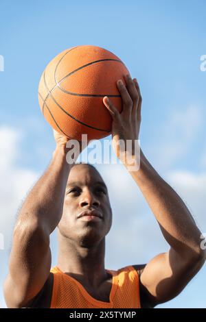 Mann hält Basketballball gegen den Himmel Stockfoto