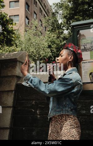 USA, New York, stilvolle Frau, die draußen Lippenstift aufträgt Stockfoto
