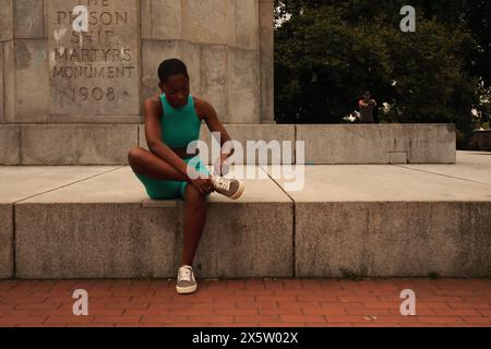 USA, New York, Frau in Sportkleidung, die am Monument sitzt Stockfoto