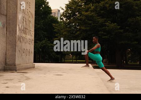 USA, New York, Frau in Sportbekleidung, die sich am Monument ausdehnt Stockfoto