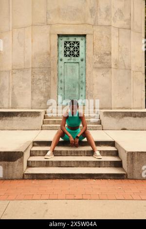USA, New York, Sportlerin in Sportkleidung sitzt am Monument Stockfoto