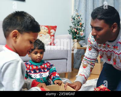 Vater und Söhne eröffnen Weihnachtsgeschenke Stockfoto