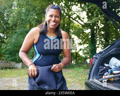 Porträt einer lächelnden Frau, die einen Taucheranzug anzieht Stockfoto