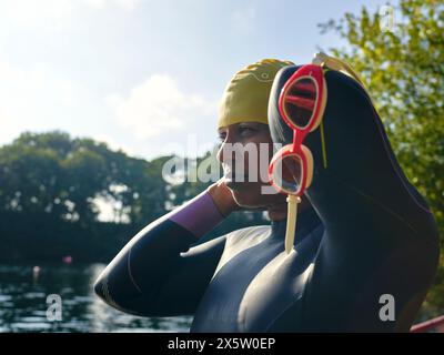 Frau im Taucheranzug, die Schwimmmütze anzieht Stockfoto