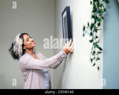 Frau hängenden Bild an Wand Stockfoto