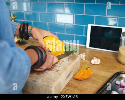 Frau, die Kürbis in der Küche hackt, Nahaufnahme Stockfoto