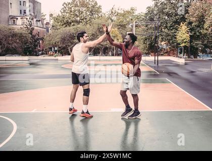 USA, Pennsylvania, Philadelphia, Männer, die High 5 auf dem Basketballfeld im Park geben Stockfoto