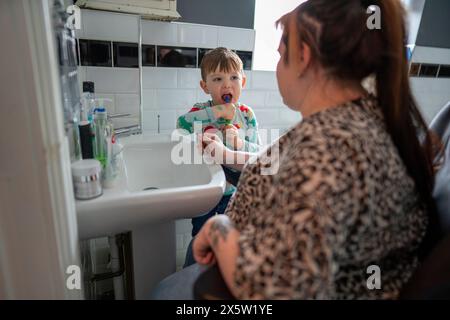 Mutter im Rollstuhl mit Sohn, der im Badezimmer Zähne putzt Stockfoto