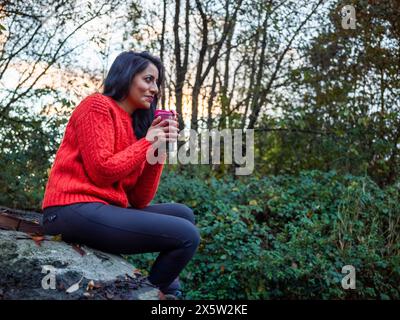 Weibliche Wanderer sitzt und trinkt heißes Getränk Stockfoto