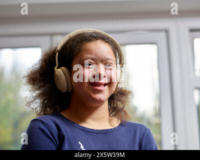 Porträt eines lächelnden Mädchens mit Down-Syndrom mit Kopfhörern Stockfoto