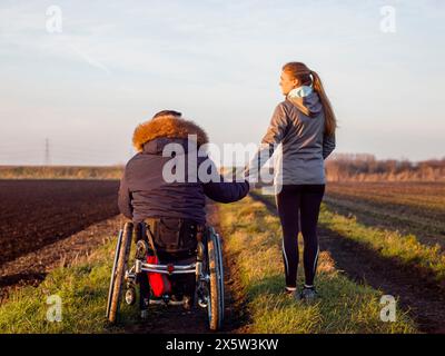 Rückansicht von Frau und Mann auf Rollstuhl im Feld Stockfoto