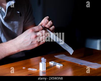 Nahaufnahme von Menschenhänden zur Vorbereitung des COVID-19-Kassettenschnelltests Stockfoto