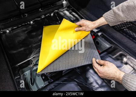 Autoservice-Mitarbeiter installieren von innen schalldämmendes Schaummaterial an der Kfz-Türverkleidung, stimmen den Kfz-Sound ab oder installieren Schalldämmung. Prozess von c Stockfoto