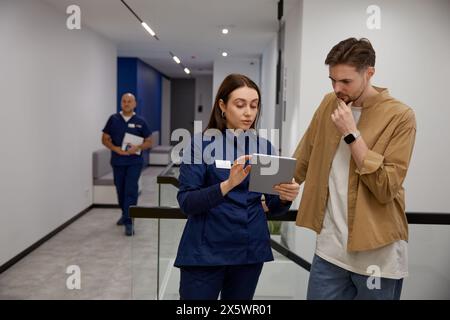 Ärztin erklärt Testergebnisse auf einem mobilen Tablet im Gespräch mit dem Patienten Stockfoto
