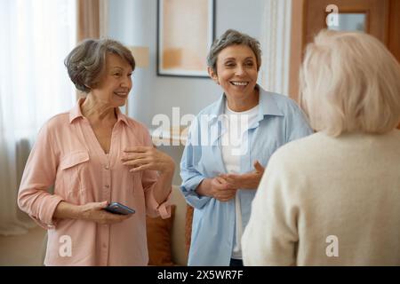Ältere Frauen Freunde lachen zu Hause im Wohnzimmer Stockfoto