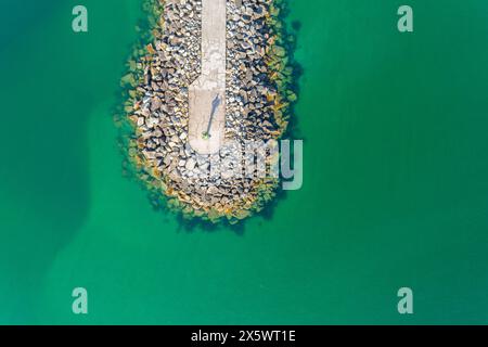 Mole aus Steinblöcken in einem Meer aus türkisfarbenem Wasser gebaut. Draufsicht mit Drohne Stockfoto