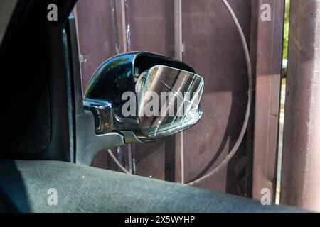 Zerbrochenes Seitenfenster des schwarzen Autos in rostfreiem Tor Hintergrund, Blick von innen Stockfoto