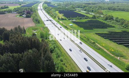 Drohnenflug auf einer deutschen Autobahn mit viel Verkehr und großen Solarpaneelen neben der Straße Stockfoto