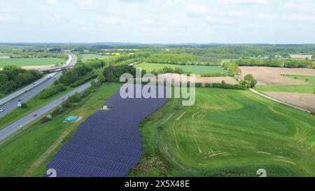 Drohnenflug auf einer deutschen Autobahn mit viel Verkehr und großen Solarpaneelen neben der Straße Stockfoto