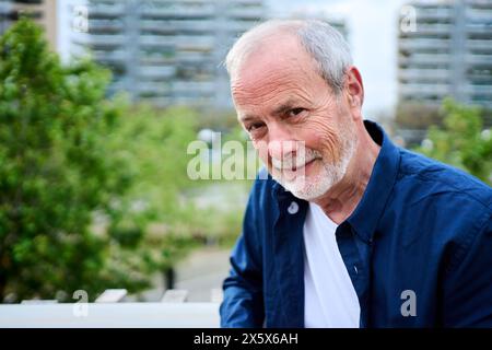 Porträt eines gesunden glücklichen kaukasischen Seniorenmannes mit grauem Haar, der draußen im Pflegeheim steht Stockfoto
