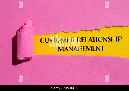 Wörter zum Kundenbeziehungsmanagement auf gerissenem rosafarbenem Papier mit gelbem Hintergrund. Konzeptionelles Symbol für das Kundenbeziehungsmanagement. Kopie s Stockfoto
