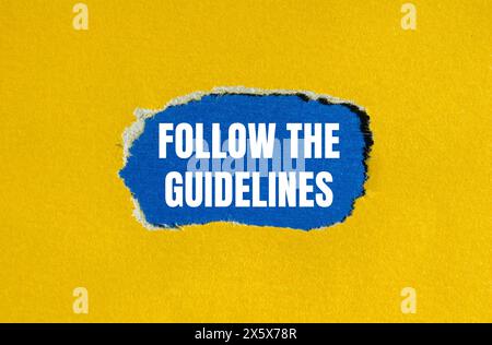 Befolgen Sie die Anweisungen auf gelbem Papier mit blauem Hintergrund. Konzeptionell Befolgen Sie das Richtliniensymbol. Kopierbereich. Stockfoto