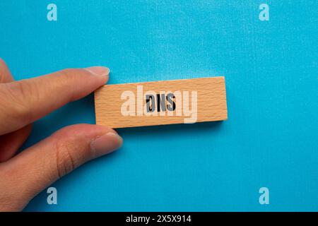 DNS-Wort auf Holzblock mit blauem Hintergrund geschrieben. Konzeptionelles DNS-Symbol. Kopierbereich. Stockfoto