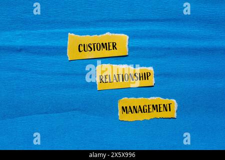 Wörter für das Kundenbeziehungsmanagement auf gerissenen gelben Papierstücken mit blauem Hintergrund. Konzeptionelles Customer Relationship Management CRM-Sym Stockfoto