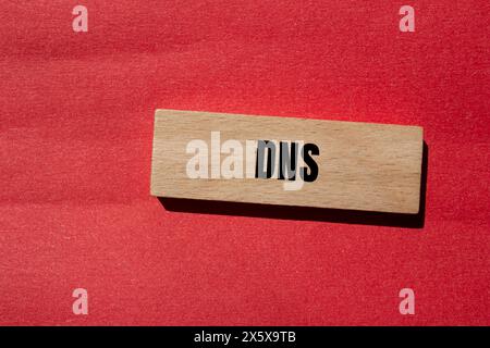 DNS-Wort auf Holzblock mit rotem Hintergrund. Konzeptionelles DNS-Symbol. Kopierbereich. Stockfoto