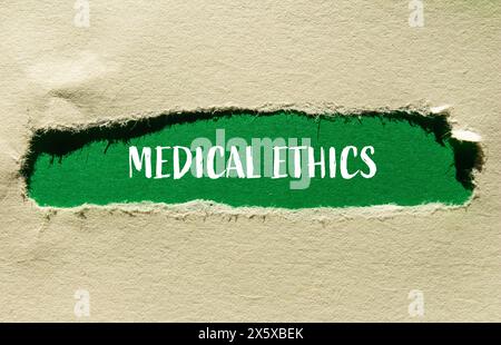 Medizinische Ethik-Wörter auf zerrissenem Papier mit grünem Hintergrund. Konzeptuelles medizinisches Ethiksymbol. Kopierbereich. Stockfoto