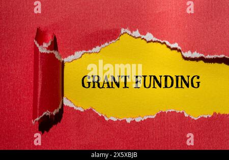 Wörter für Zuschüsse auf gerissenem rotem Papier mit gelbem Hintergrund. Konzeptionelles Finanzierungskonzept für Geschäftszuschüsse. Kopierbereich. Stockfoto