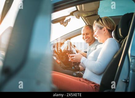 Glücklich lächelnd zwei junge Adulds Paare verwenden Smartphone-Navigation im Auto während Auto Jorney. Sie lachen während der Fahrt. Familie, Paare Stockfoto
