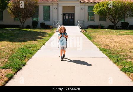 Kinderpuppe mit Rucksäcken im Park in der Nähe der Schule. Schuljunge mit Rucksäcken im Freien. Bildungskonzept für Kinder. Stockfoto