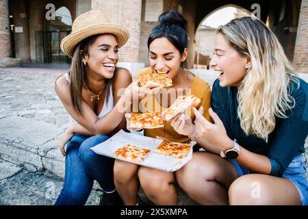 Multirassische Touristenfreunde, die Spaß beim Essen italienischer Pizza im Urlaub haben Stockfoto