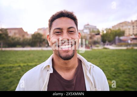 Hübscher, glücklicher, bärtiger Mann. Porträt eines fröhlichen jungen Mannes, der draußen steht und vor der Kamera lächelt. Stockfoto