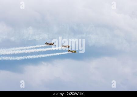 Flugzeuggeschwader fliegen mit Farbspuren in weißen Linien über Wolken und klaren Himmel, begeben Sie sich in die faszinierende Welt der Kunstflugkunst, fliegen Sie Inspirationen. Ba Stockfoto