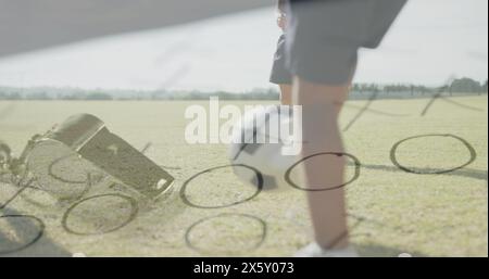 Bild von Pfeife und Spielplan über glücklichen, vielfältigen Schuljungen, die Fußball spielen Stockfoto