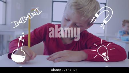 Bild von Wissenschaftssymbolen über glücklichem kaukasischen Schuljungen, der am Schreibtisch arbeitet Stockfoto