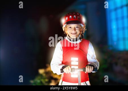 Kind in reflektierender Weste im Dunkeln. Sicherheit auf dunklen Straßen für Schulkinder. Sicherer Weg nach Hause in der Nacht oder am Abend. Fluoreszierende Streifen Stockfoto