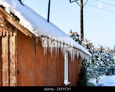 Im Winter hängen Eiszapfen vom Dach des Hauses. Stockfoto