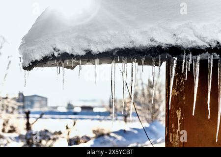 Im Winter hängen Eiszapfen vom Dach des Hauses. Stockfoto