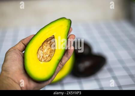 Frau mit reifer geschnittener Avocado. Nahaufnahme der Hände, die frische Avocado halbieren. Stockfoto