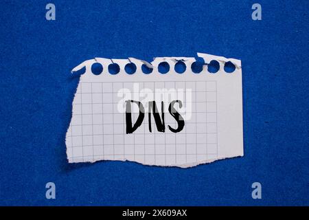 DNS-Wort auf gerissenem weißem Papier mit blauem Hintergrund geschrieben. Konzeptionelles DNS-Symbol. Kopierbereich. Stockfoto